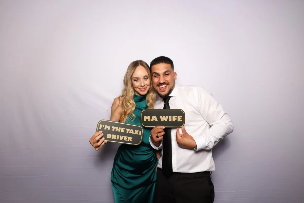 A couple holding up props in the photobooth