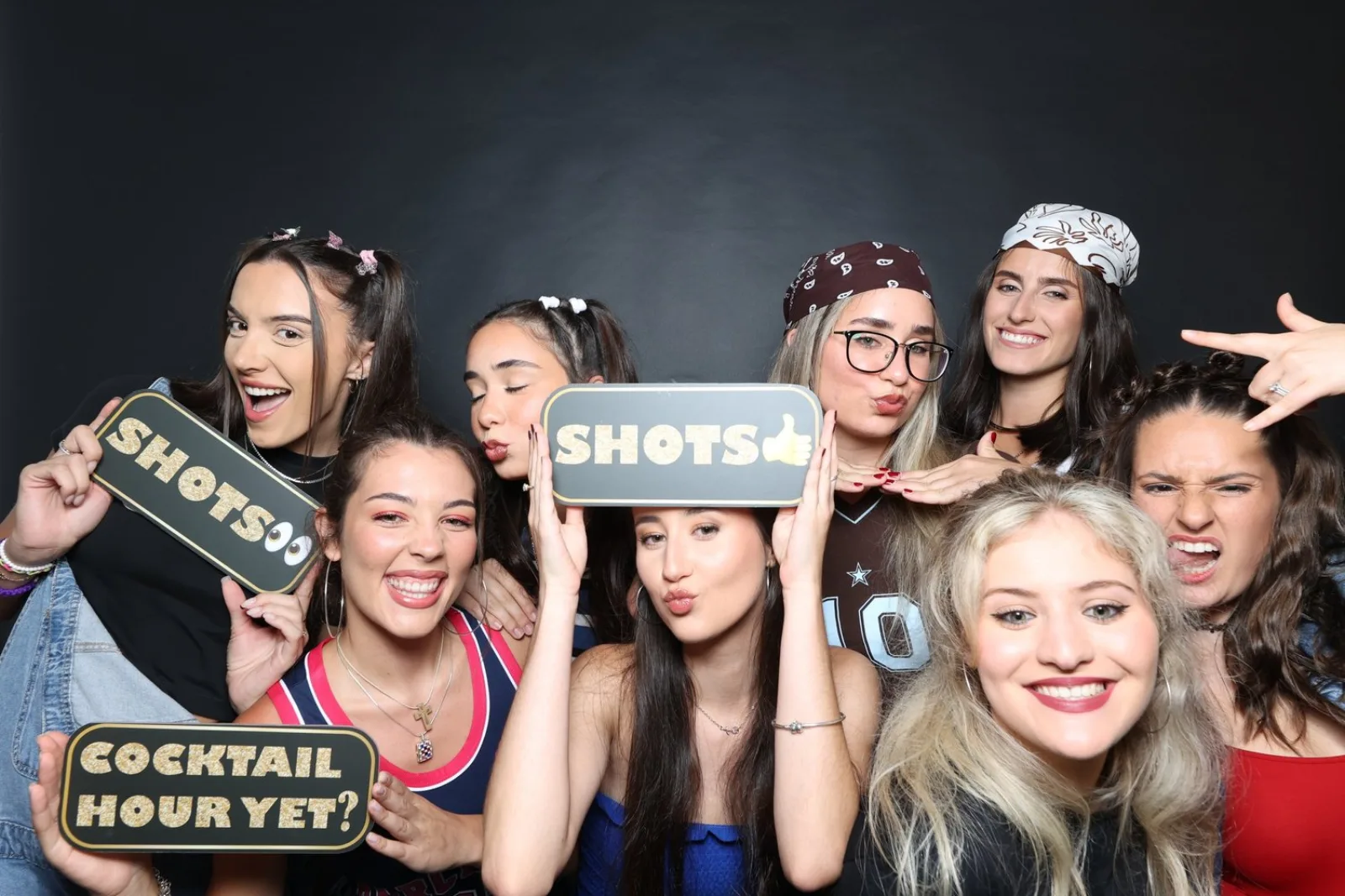 Guests laughing with props in front of the photobooth backdrop