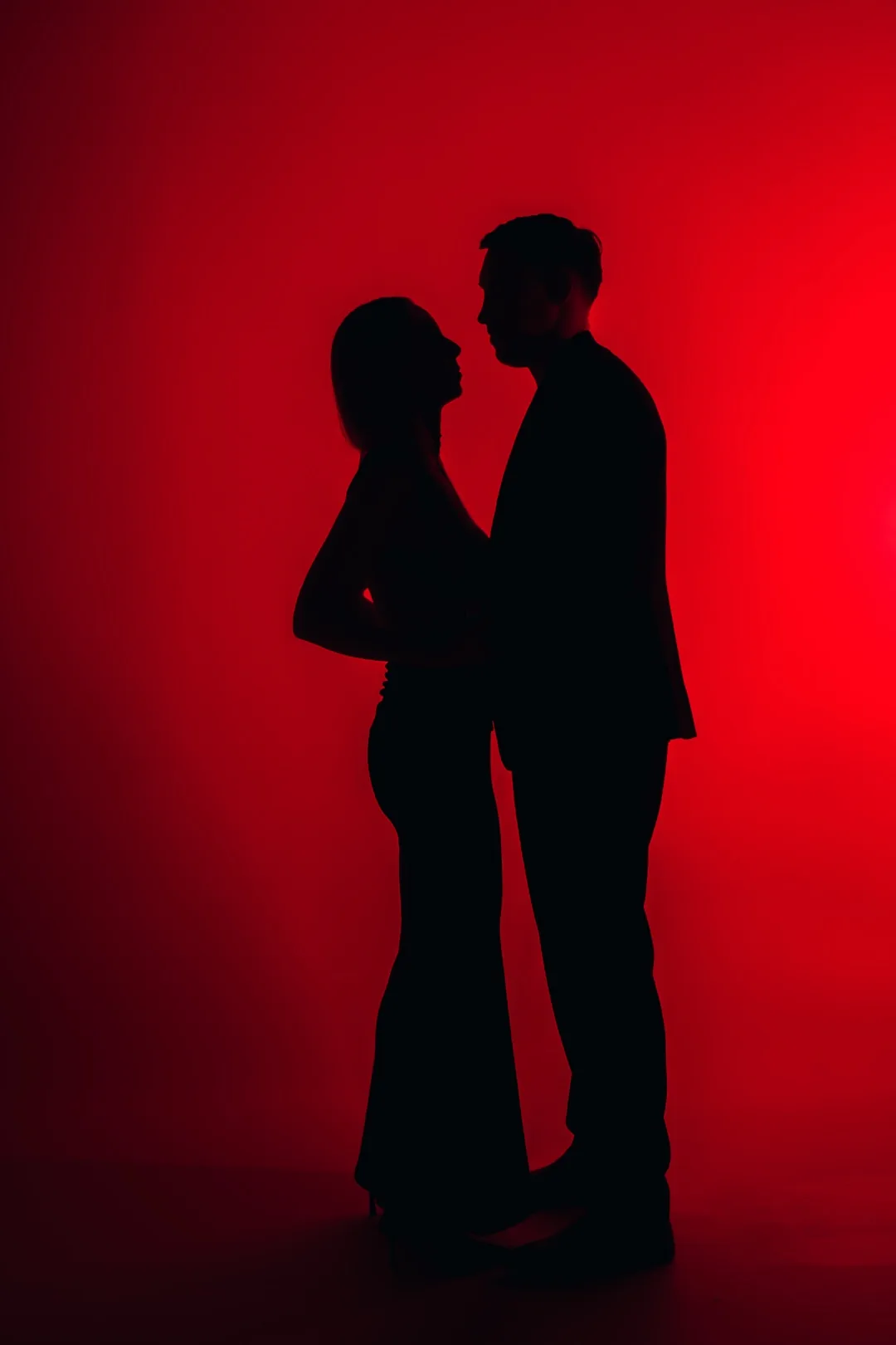 Couple silhouetted against red light in the studio